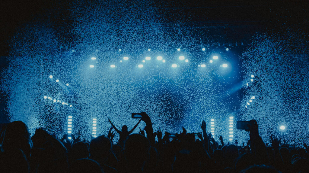 Crowd view of concert with blue lights and confetti