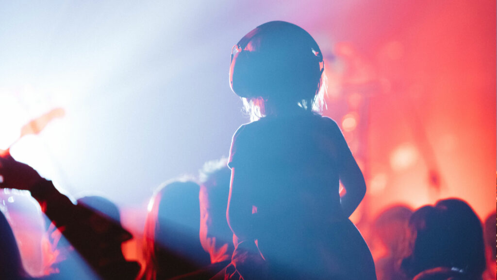 Child sitting on parent shoulder in a concert