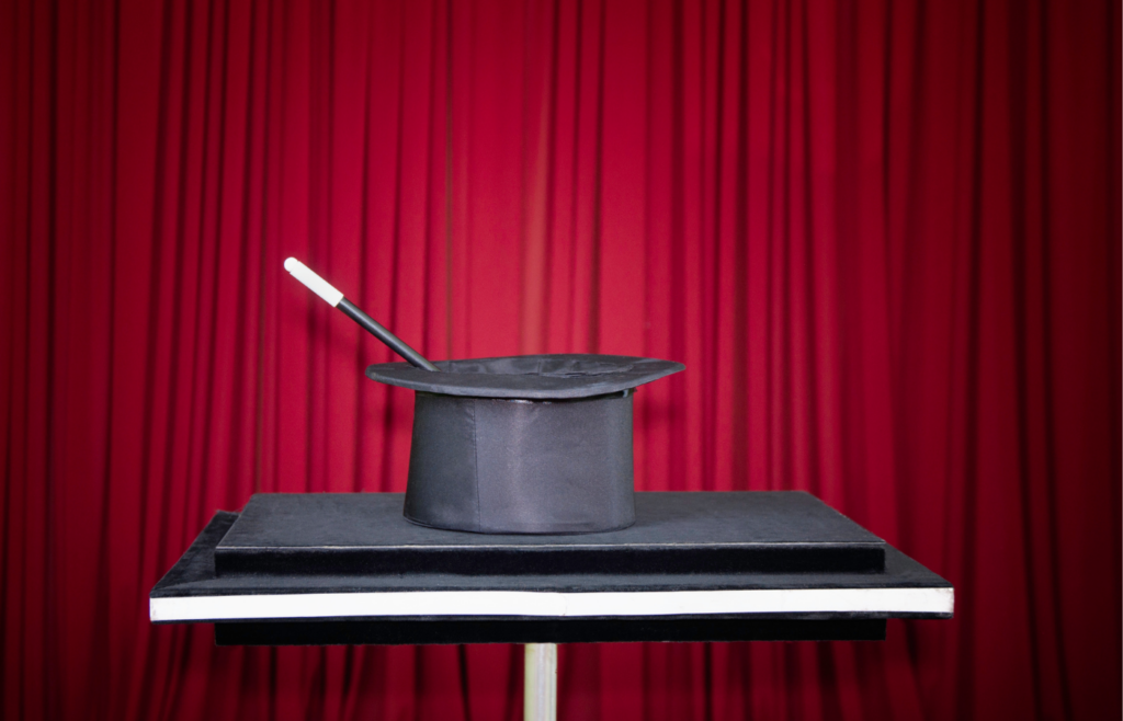 magicians hat and wand with red curtain backdrop